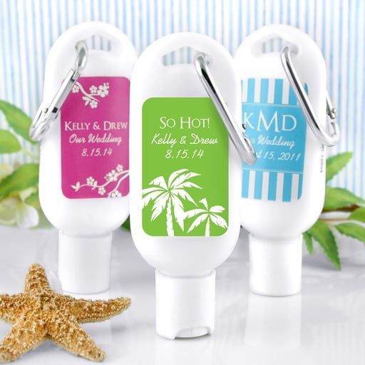 Three customized white hand sanitizer bottles with carabiners, decorated with wedding labels, placed near a starfish.