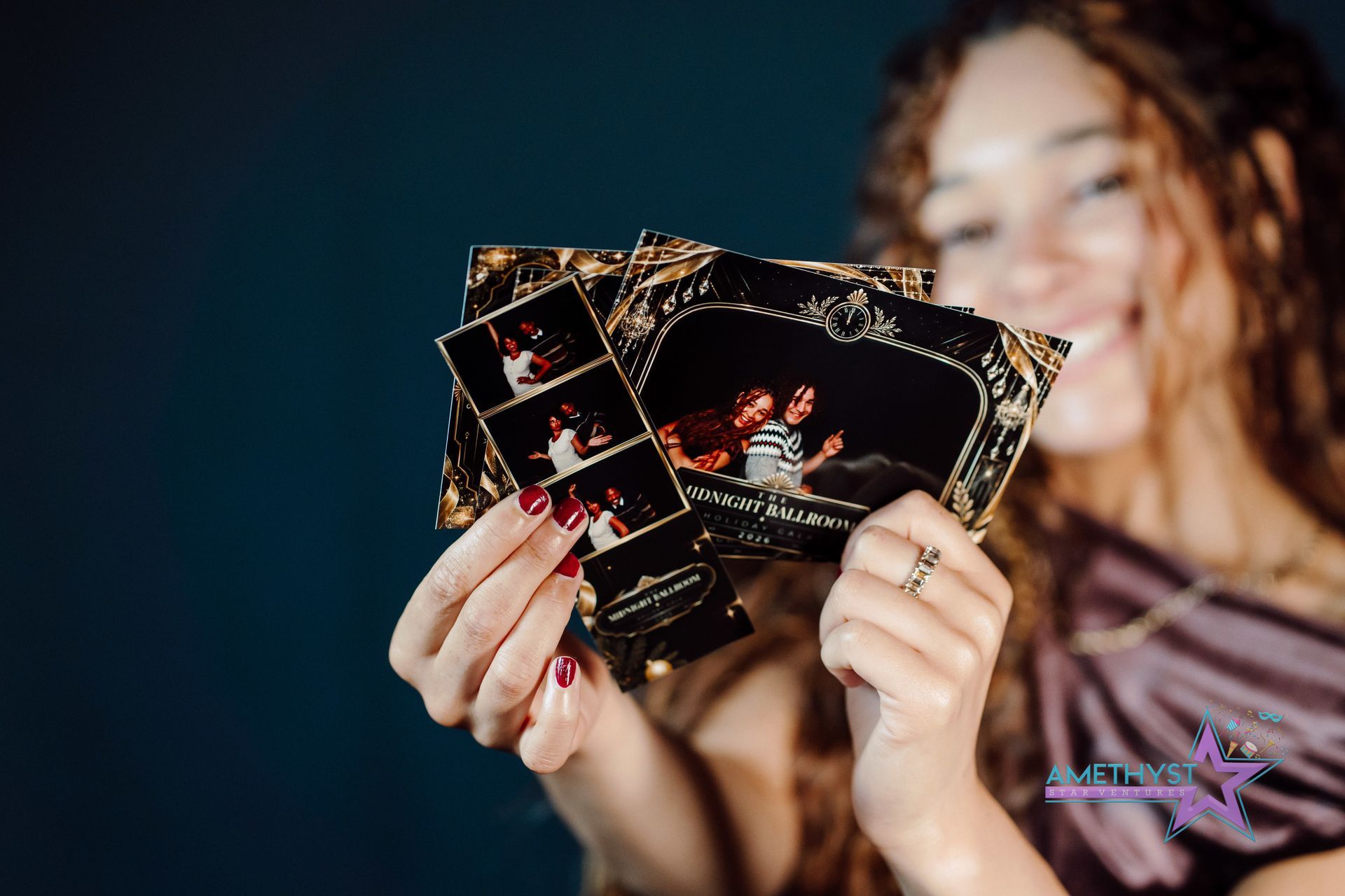 Person holding several photo prints fanned out against a dark blue background