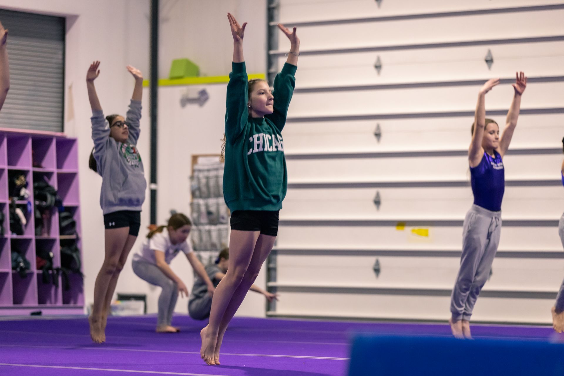 A group of young girls are practicing gymnastics in a gym.