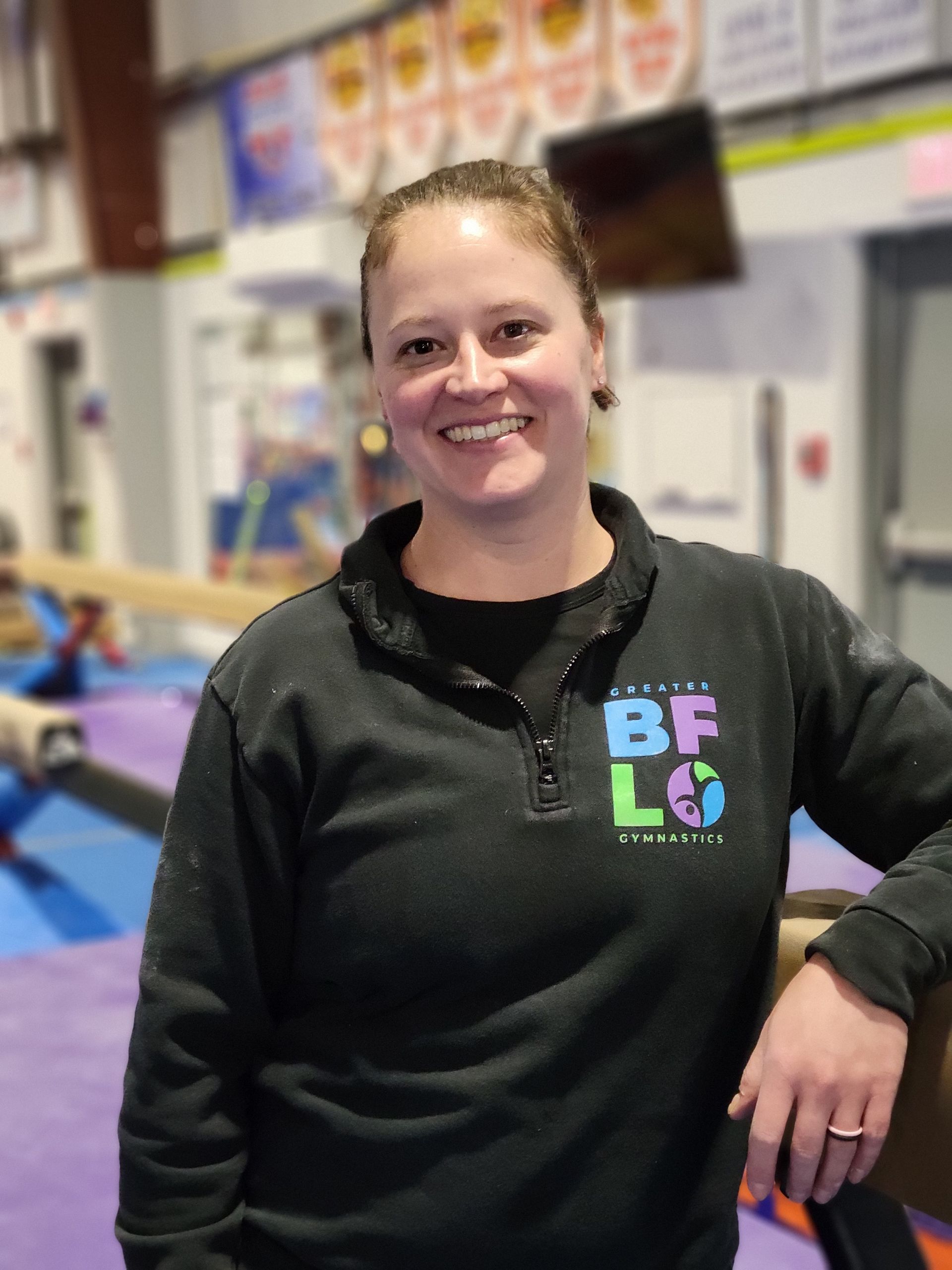 A woman is helping a child do a handstand in a gym
