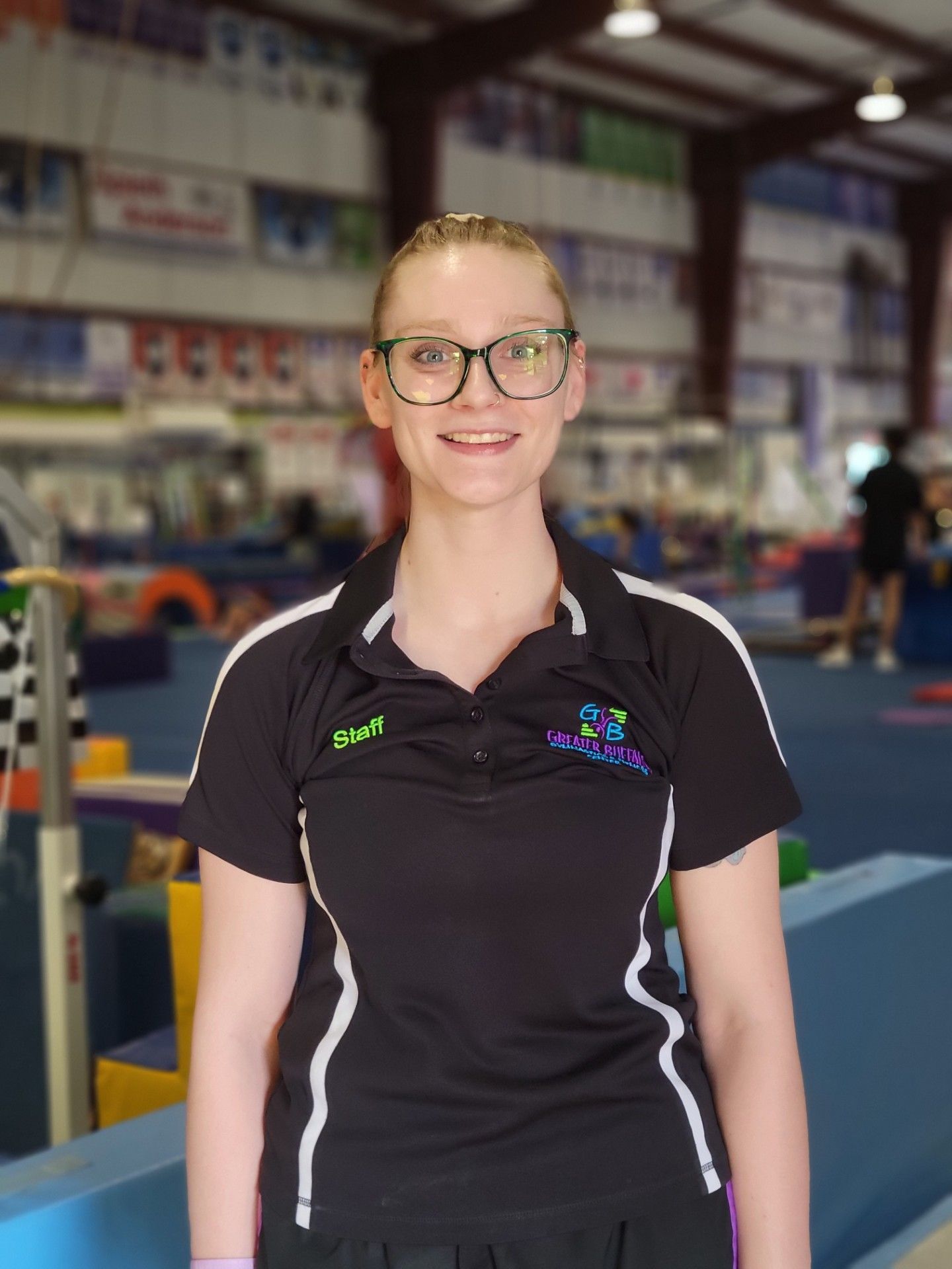 A woman in a black shirt is standing in a gym.