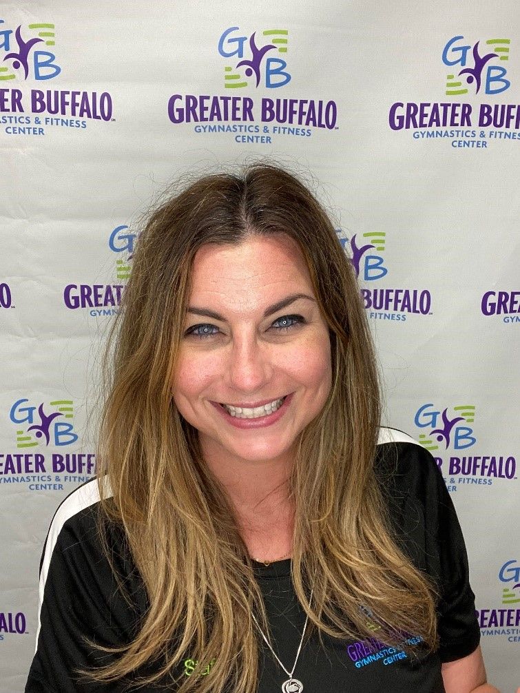 A woman is smiling in front of a greater buffalo sign.