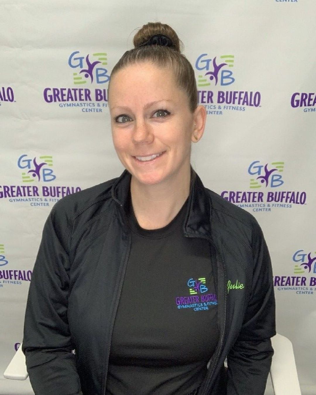 A woman is smiling in front of a greater buffalo sign