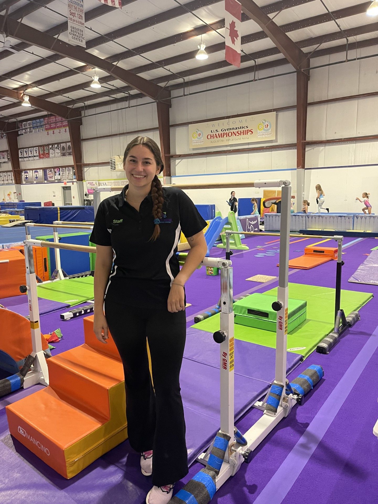 A woman is standing next to a bar in a gym.