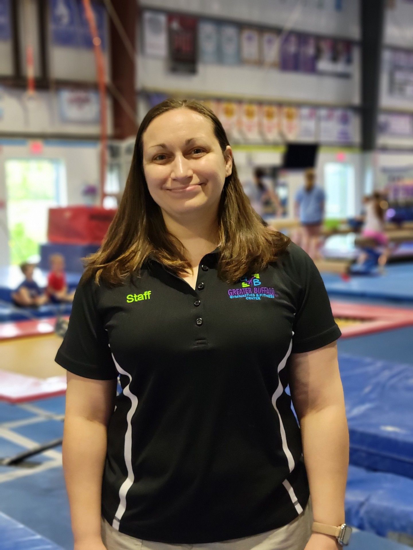 A woman is helping a young girl do a handstand on a balance beam.