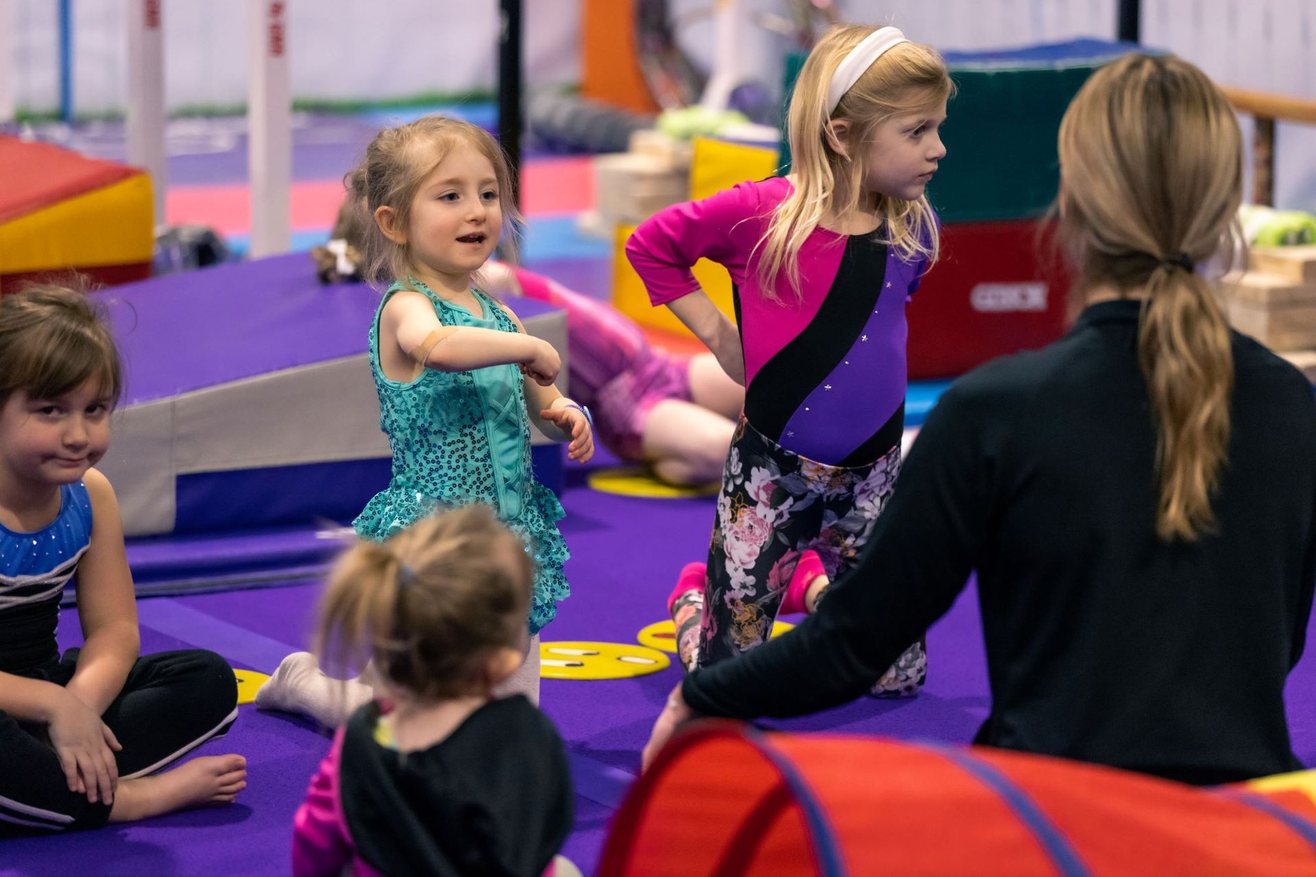 A group of young girls are practicing gymnastics in a gym.