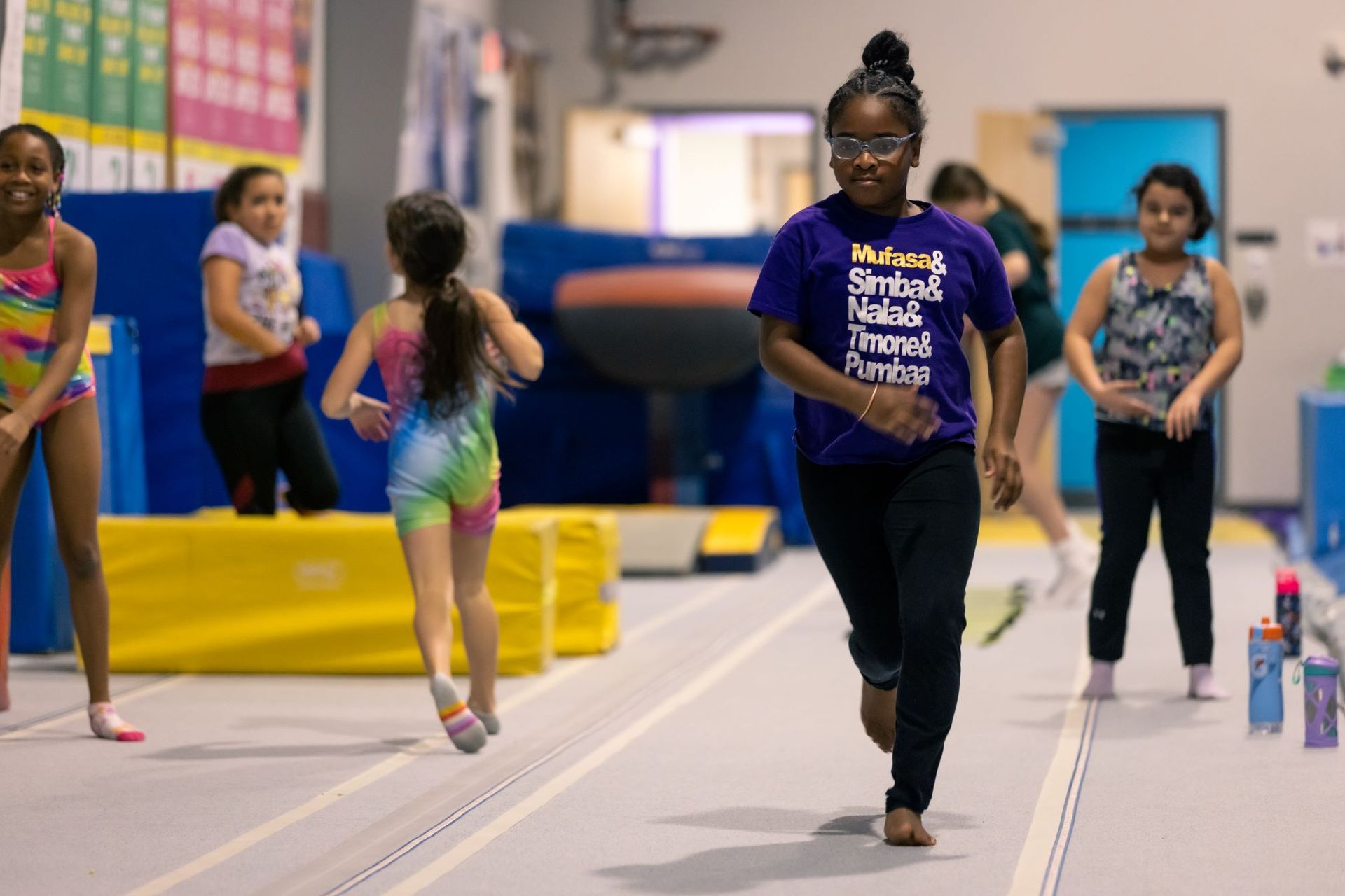 A group of young girls are practicing gymnastics in a gym.