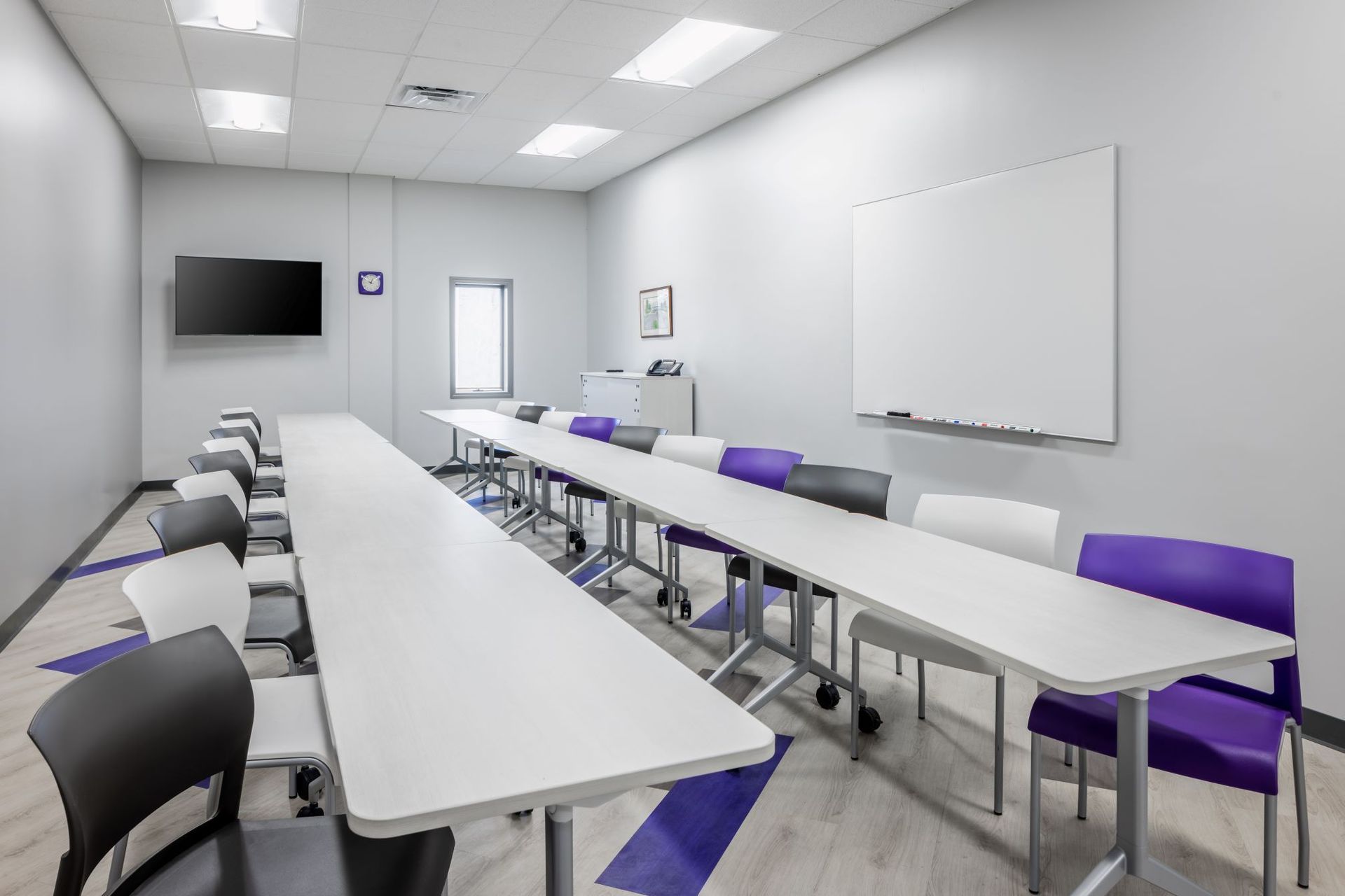 A conference room with long white tables and purple chairs.