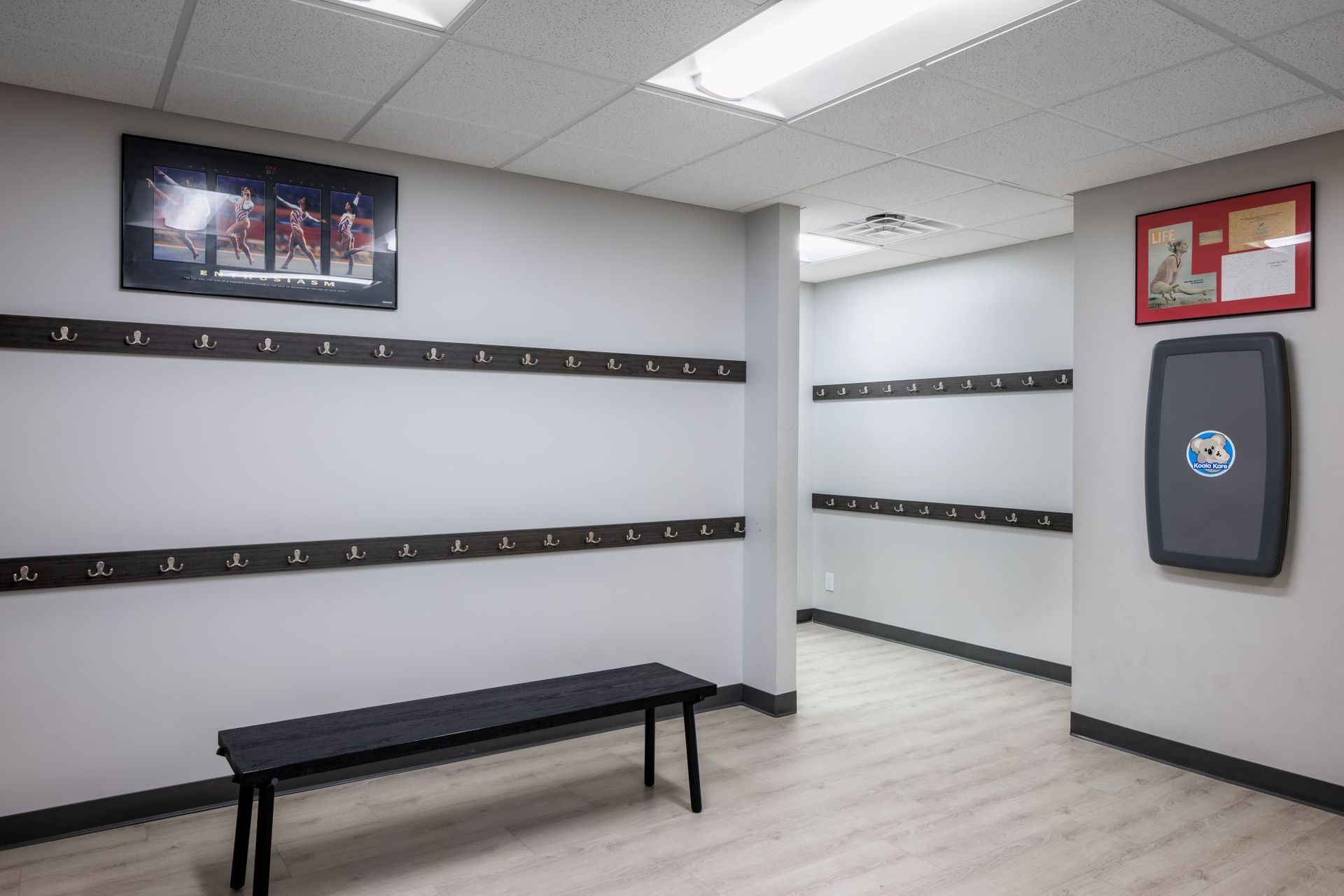 A locker room with a bench and a picture on the wall.