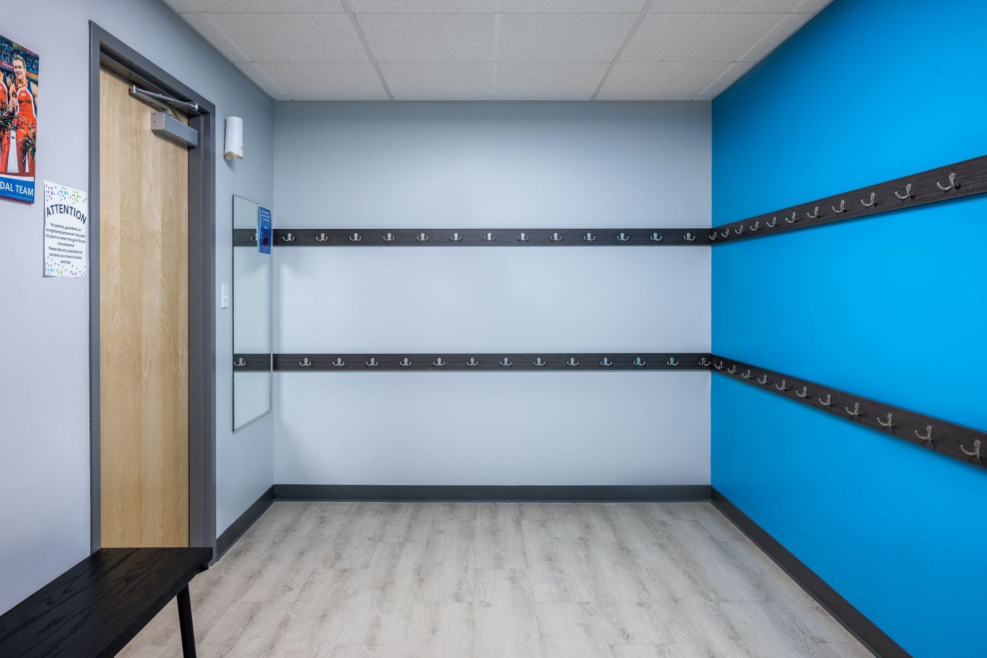 An empty locker room with blue walls and a bench