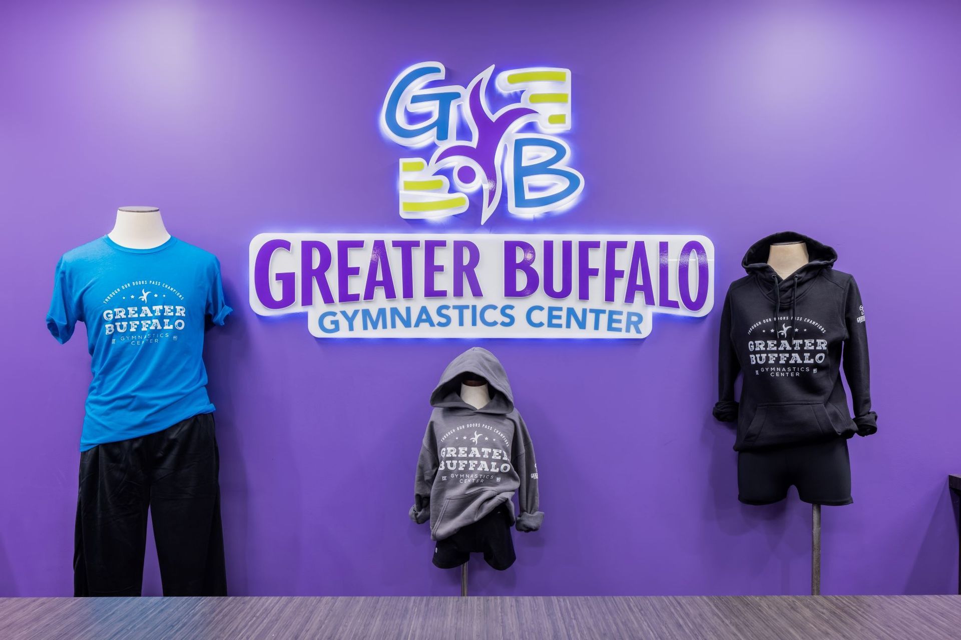 A purple wall with a sign that says greater buffalo gymnastics center.