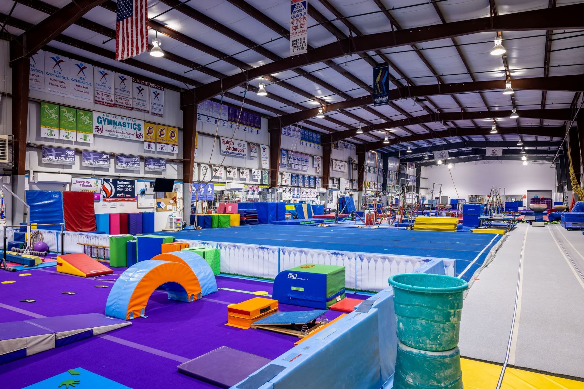 A large gym filled with a variety of gymnastics equipment.