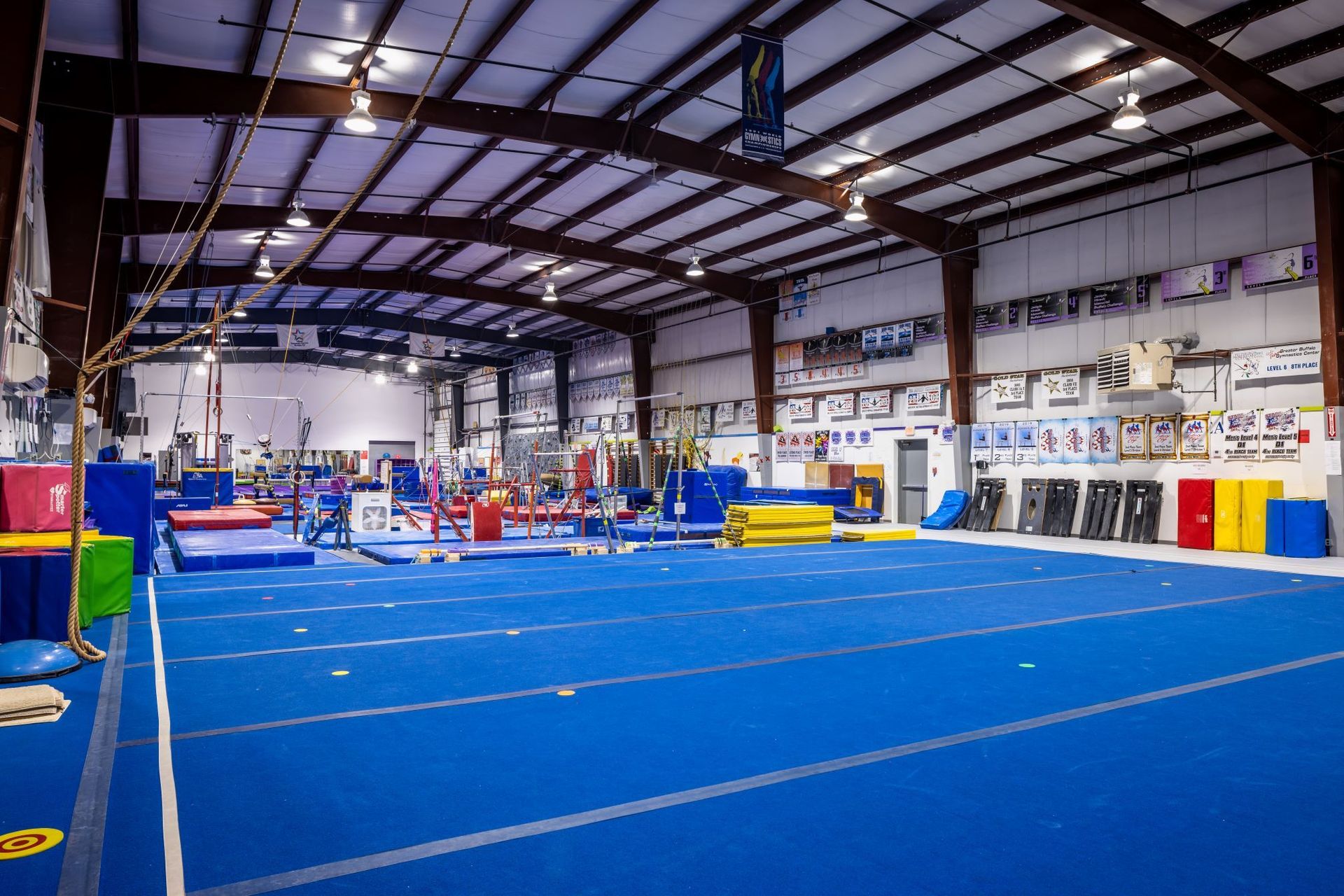 A large gym with a blue mat and a lot of equipment.