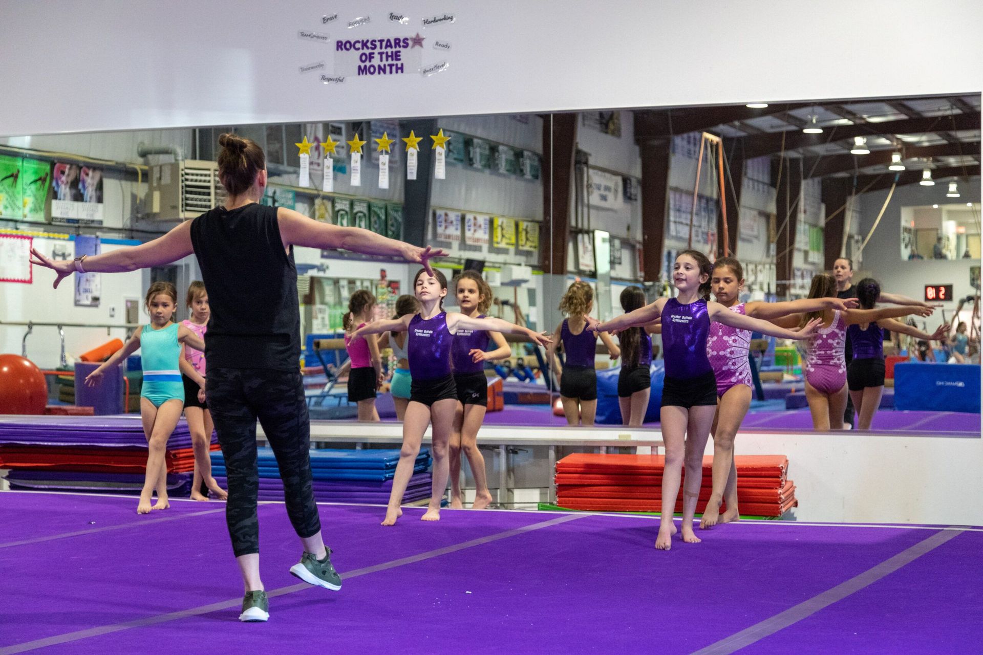 A group of young girls are practicing gymnastics in a gym.