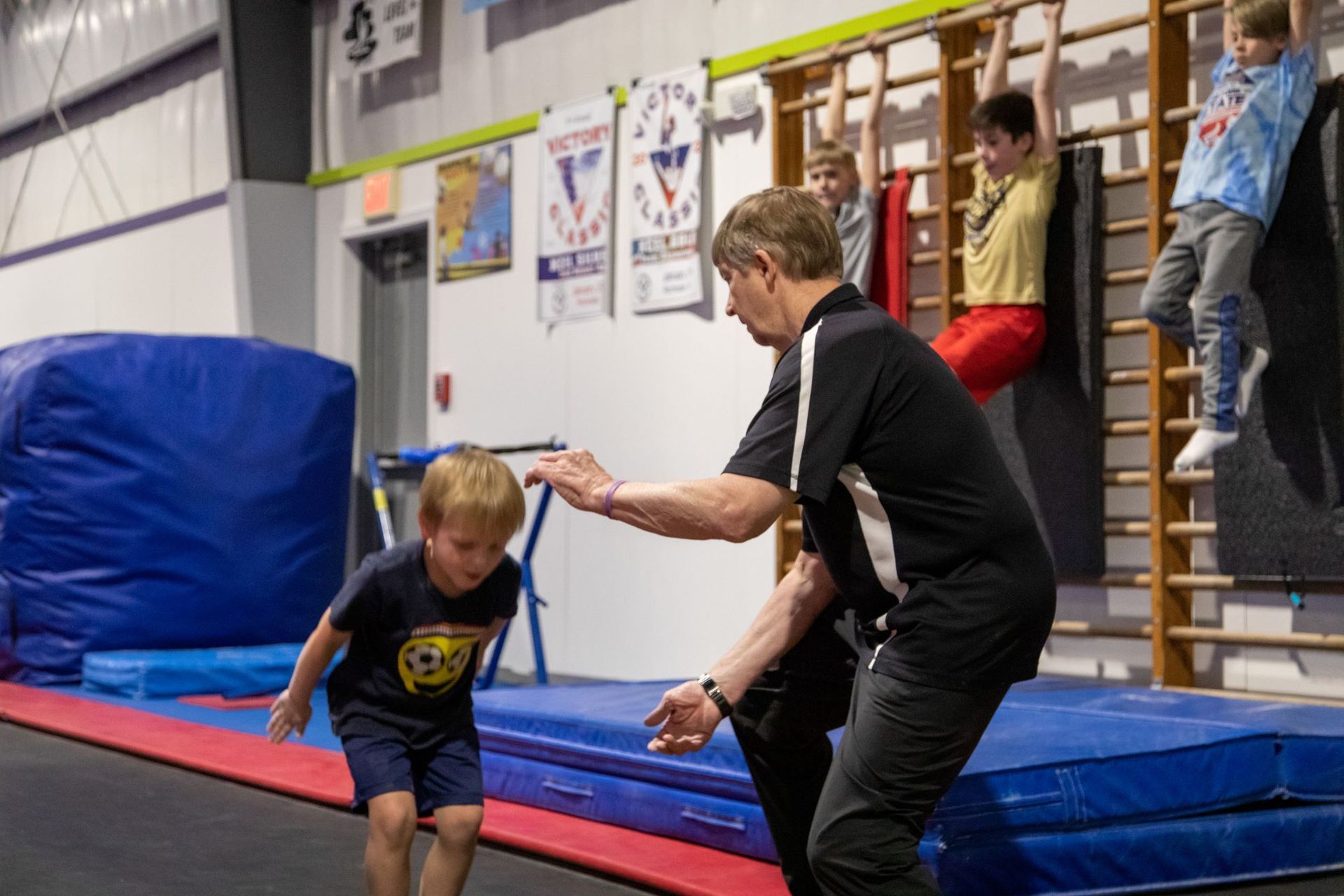 A man is helping a young boy do a trick on a trampoline.