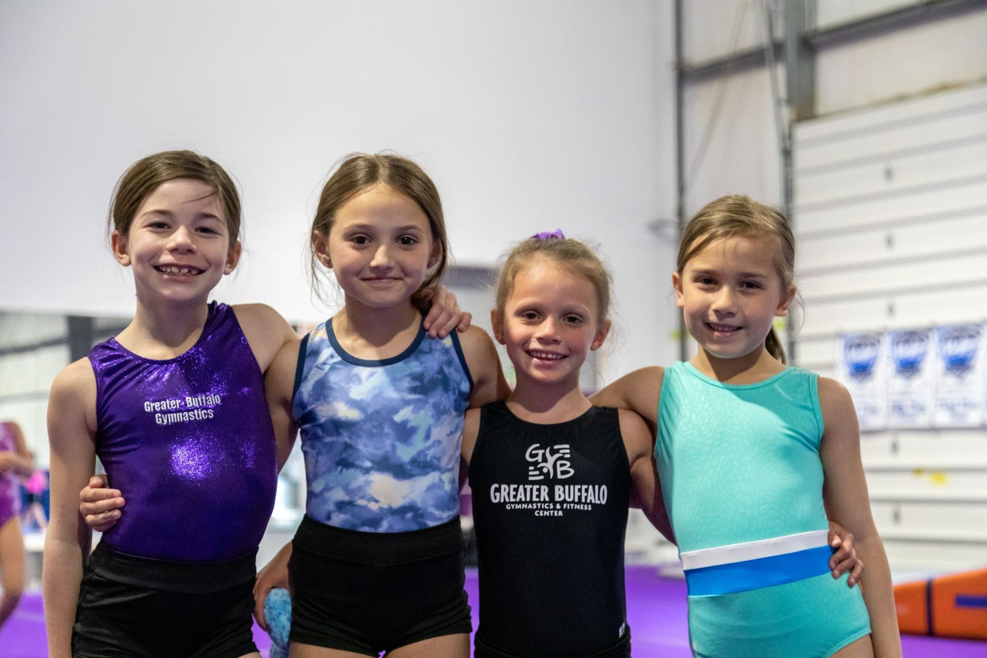 A group of young girls are practicing gymnastics in a gym.