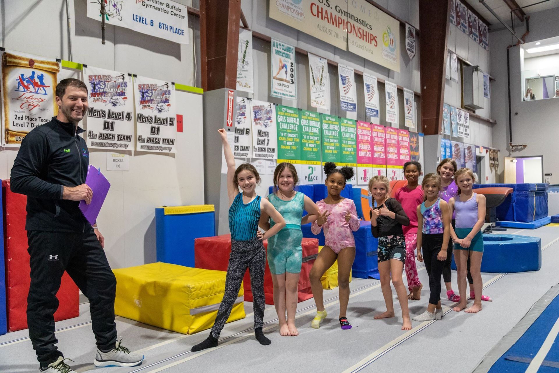 A group of young girls are posing for a picture with a man in a gym.