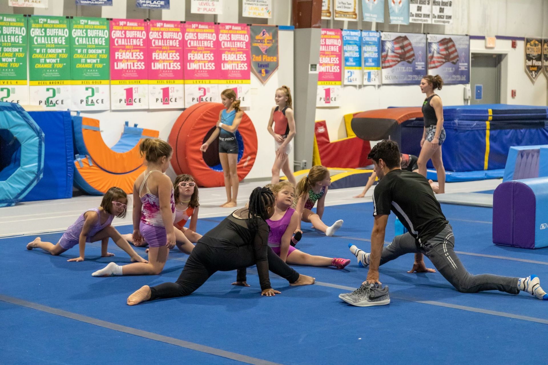 A group of young girls are doing stretching exercises in a gym.