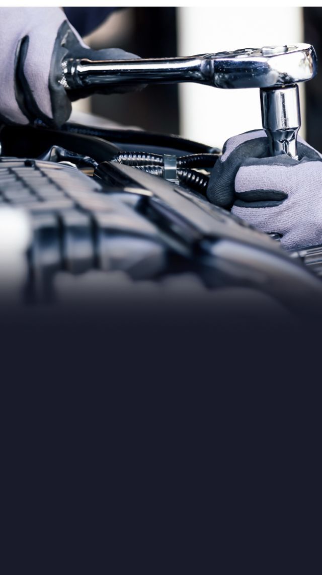 An automotive shop with five cars parked outside. Yellow building with a sign that reads,