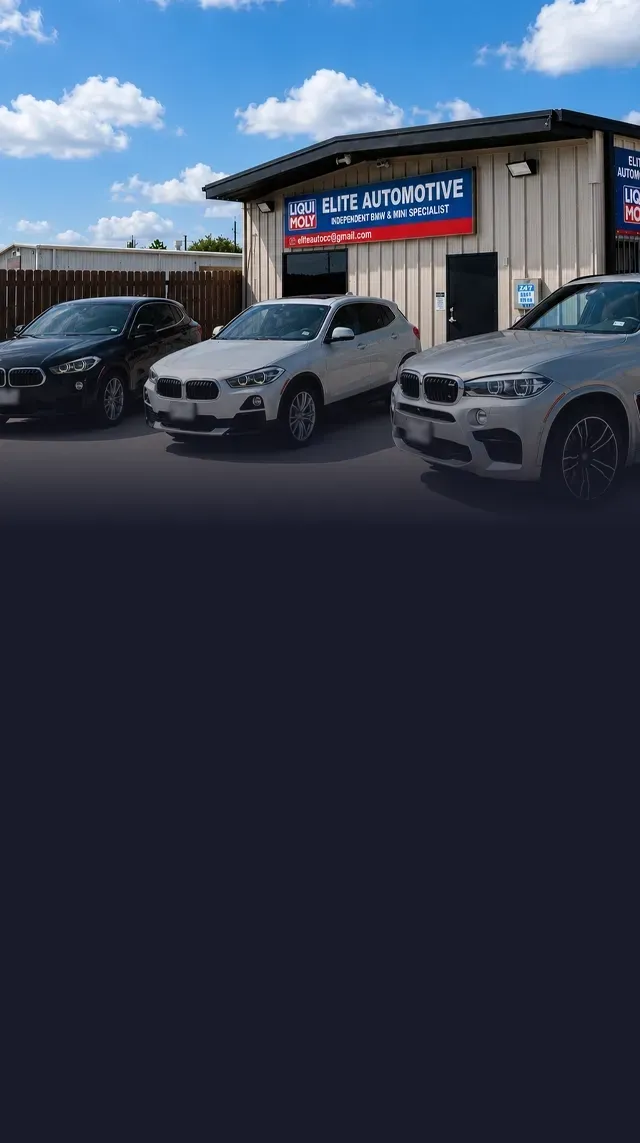 An automotive shop with five cars parked outside. Yellow building with a sign that reads, 