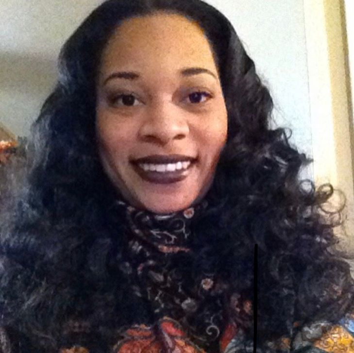 A woman with long curly hair is smiling for the camera