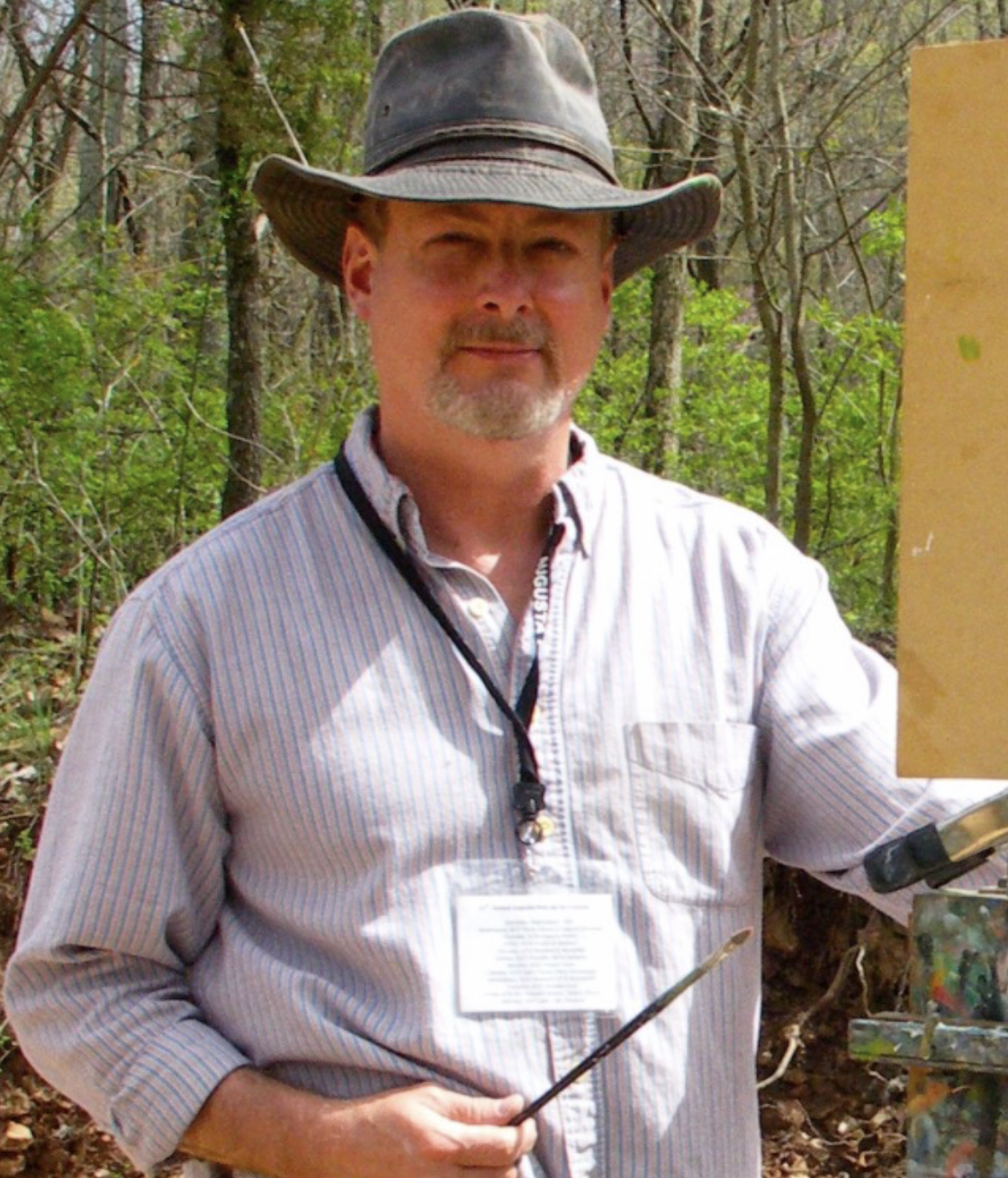 A man wearing a cowboy hat is holding a brush