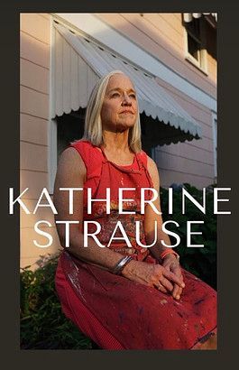 A woman in a red dress is sitting in front of a pink building.