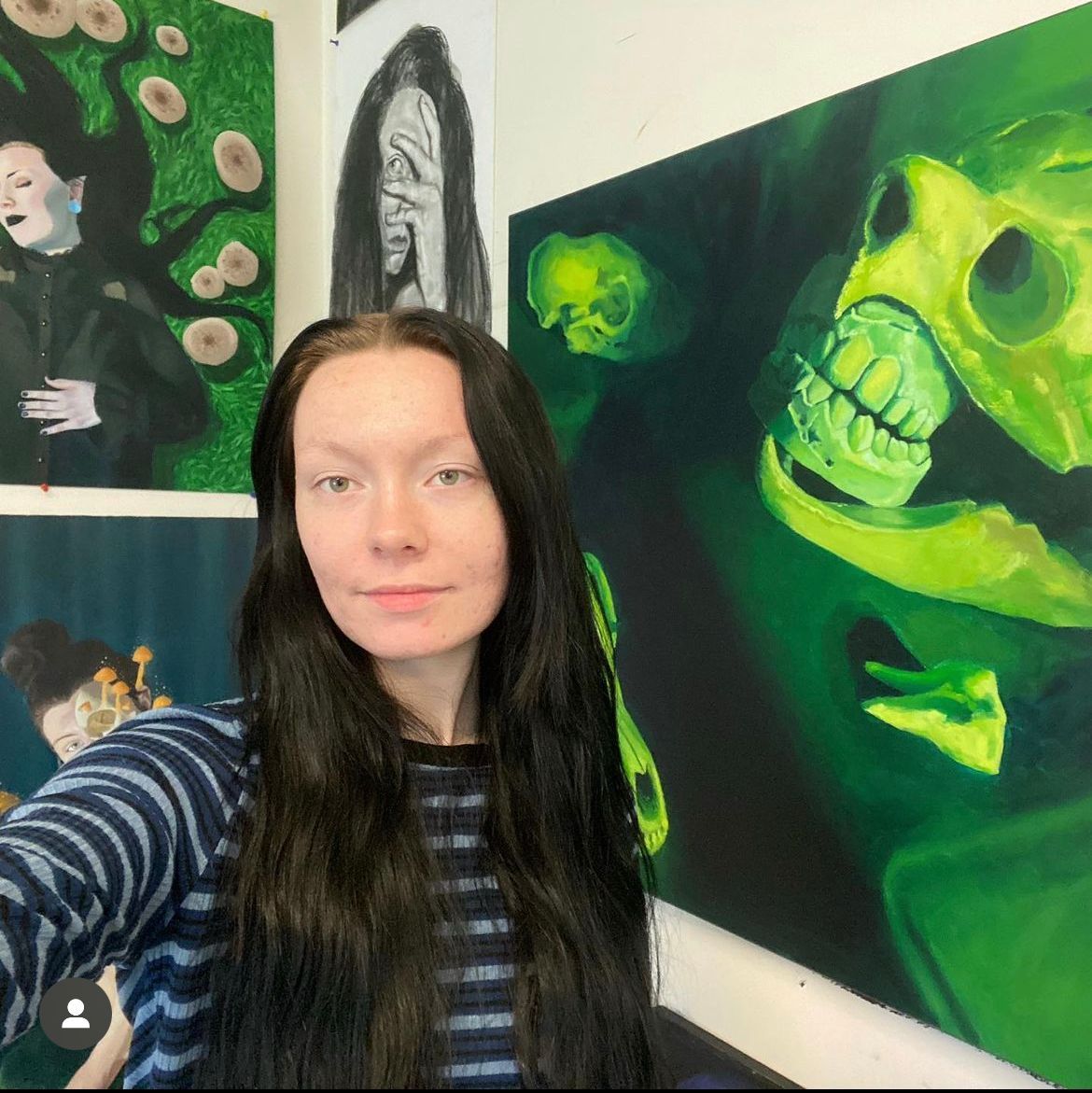 A woman is taking a selfie in front of a painting of a skull