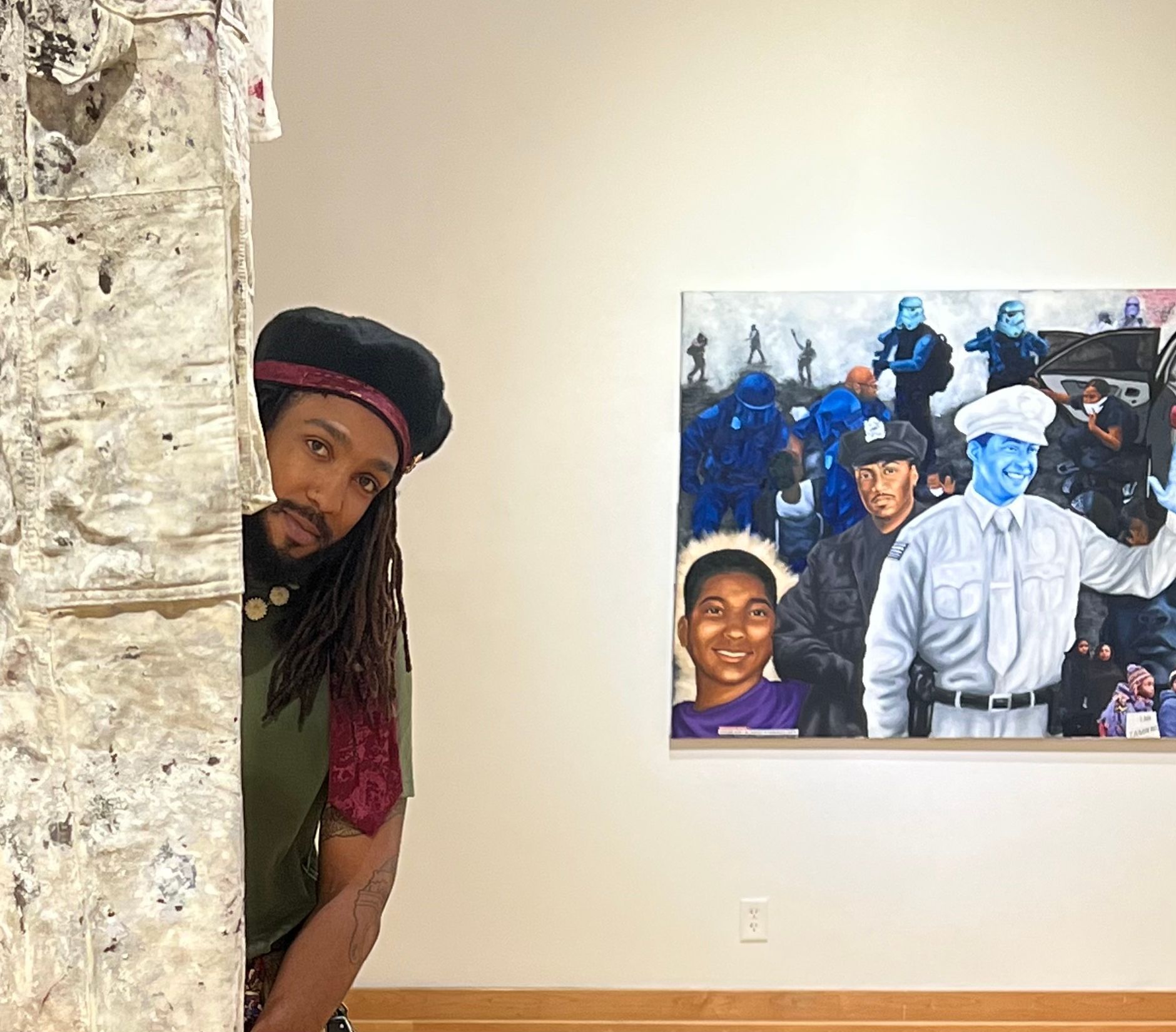 A man is peeking out from behind a wall next to a painting.