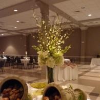 Elegant banquet hall with tall floral centerpieces and round tables under soft lighting