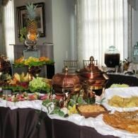 Buffet table with copper chafing dishes, salads, and pastries in a bright dining room