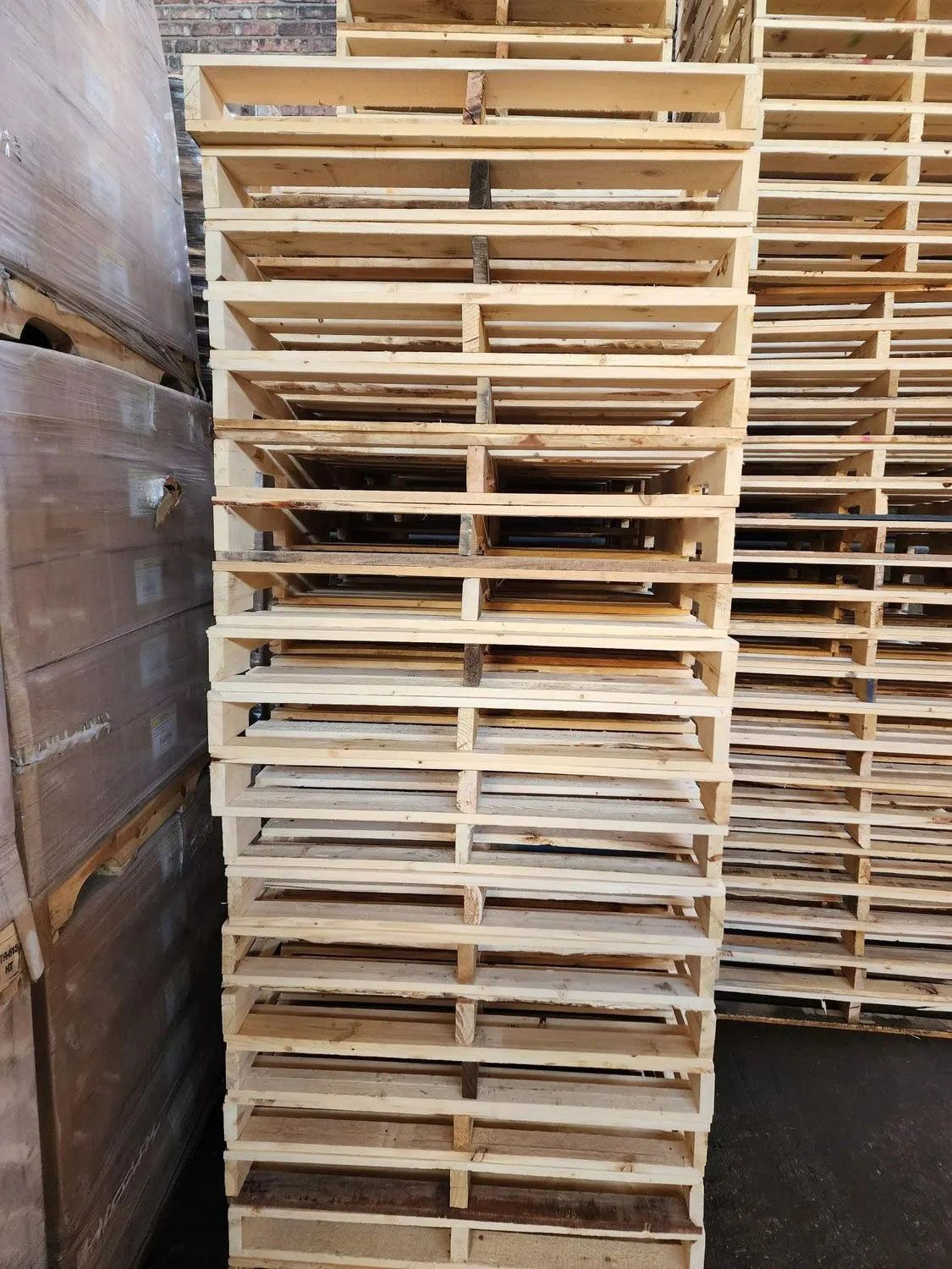 A stack of wooden pallets are stacked on top of each other in a warehouse.