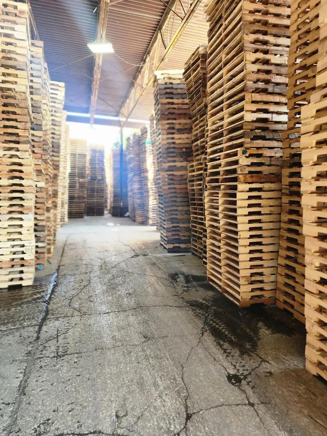A warehouse filled with lots of wooden pallets stacked on top of each other.