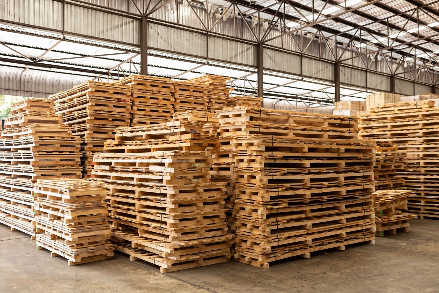 A warehouse filled with lots of wooden pallets stacked on top of each other.
