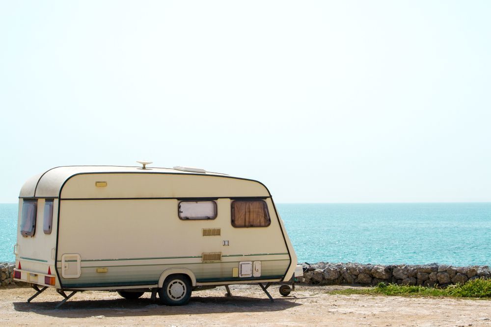 Beige Camper Trailer Parked Near the Ocean Under a Bright Blue Sky — Darren's Caravan Repairs in Lake Macquarie, NSW