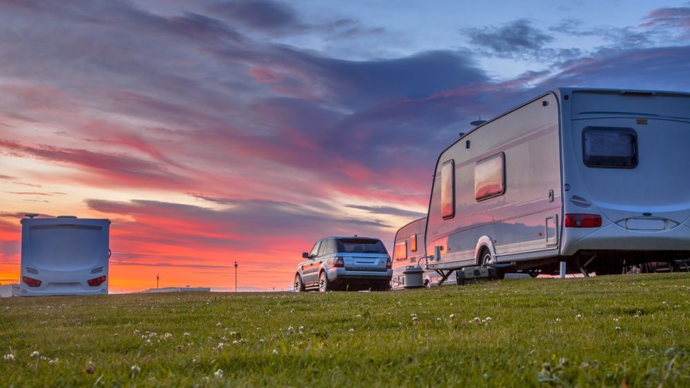 Campers on a Grassy Field With a Car, Under a Colourful Sunset Sky — Darren's Caravan Repairs in Warners Bay, NSW