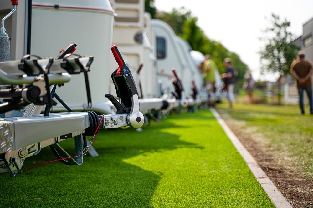 Row of Caravans Parked on Green Artificial Turf, People in Background — Darren's Caravan Repairs in Warners Bay, NSW