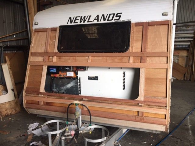 Caravan Front With Exposed Wooden Frame, Window, and Gas Tanks — Darren's Caravan Repairs in Warners Bay, NSW