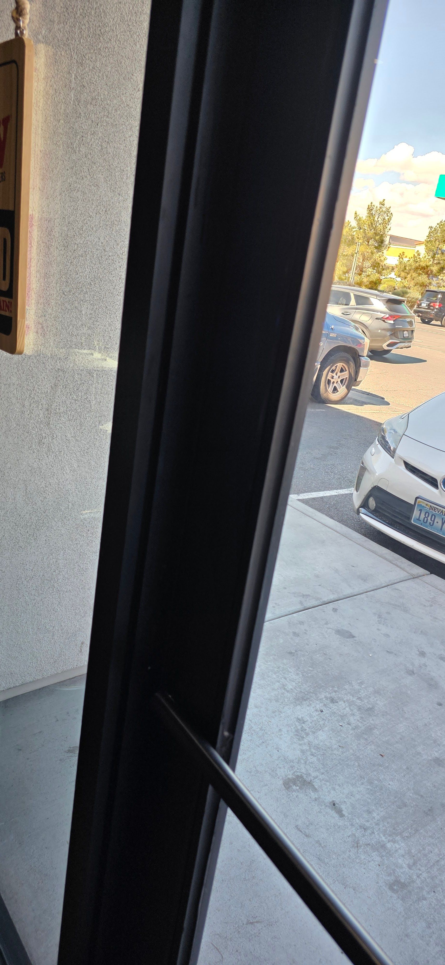 View through a window, black frame, cars in parking lot.