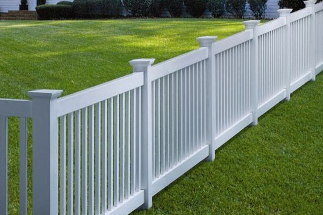 A white fence is sitting on top of a lush green lawn.