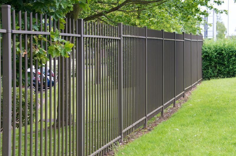 A metal fence surrounds a lush green field.