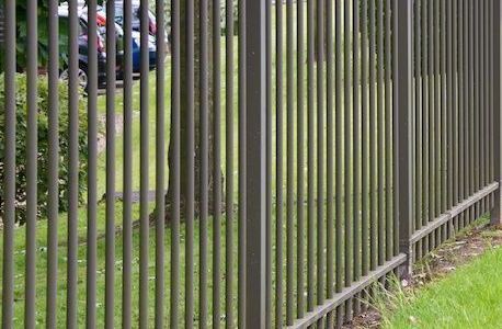 A metal fence surrounds a lush green field.