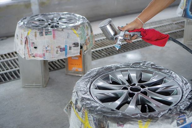 Paint Correction — Worker Painting Light Alloy Wheel With Spray in Springfield, OH