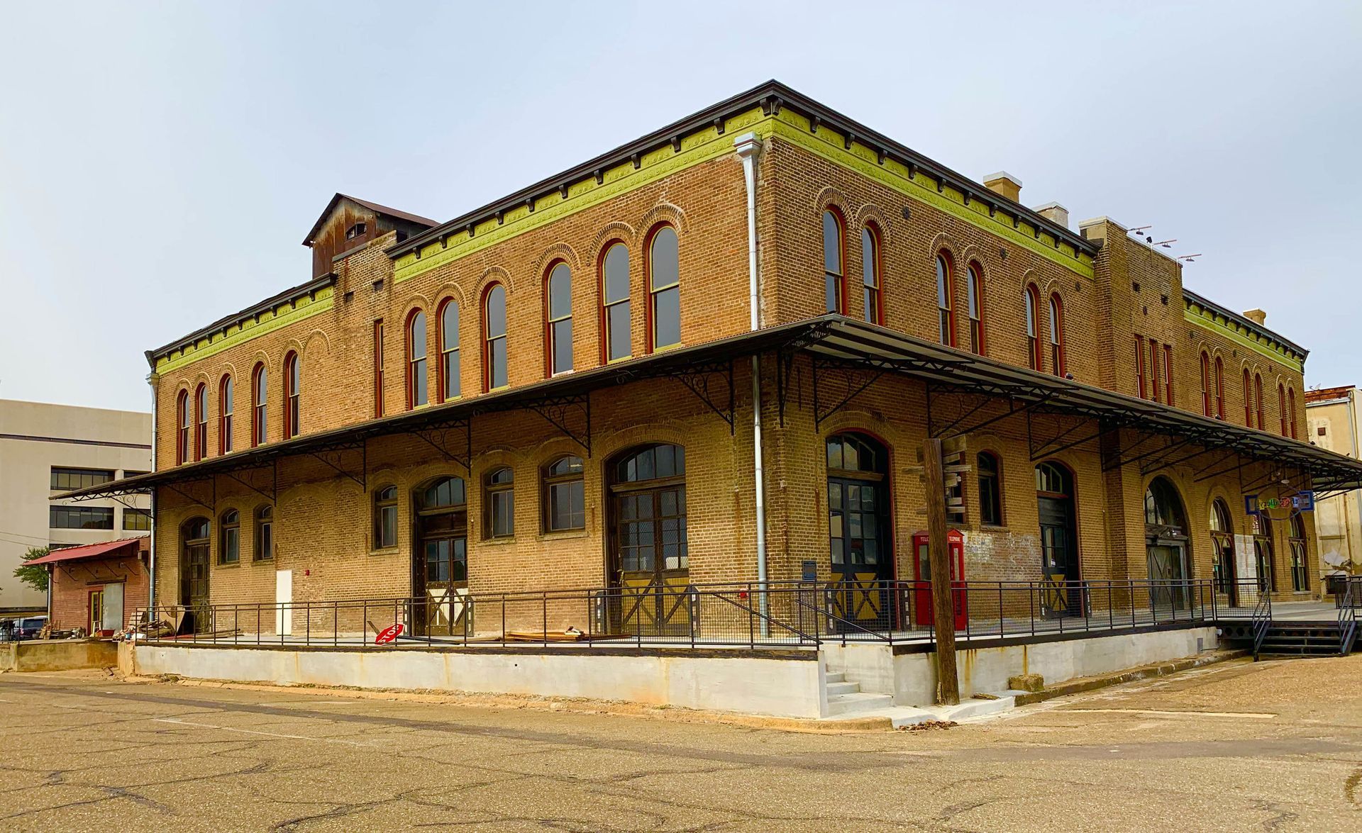 Two-story brick building with arched windows, a covered porch, and a light-colored ground area.