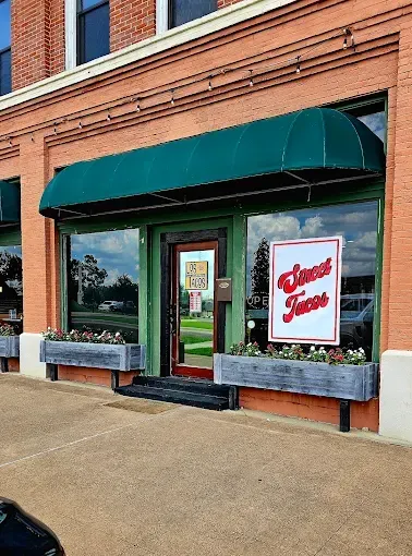 Taco restaurant storefront with green awning, large windows, and a sign that reads