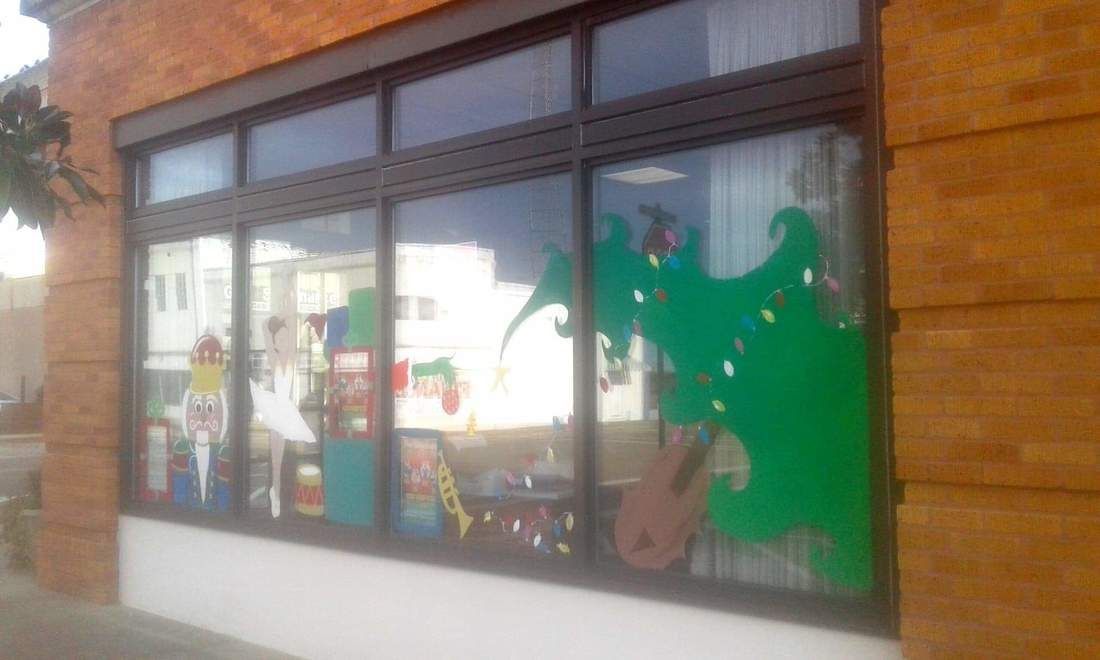 Storefront window display with colorful decorations, including a large green shape and visible items inside.