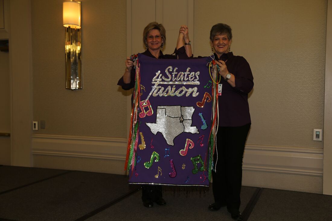 Two women hold up a purple banner that says 