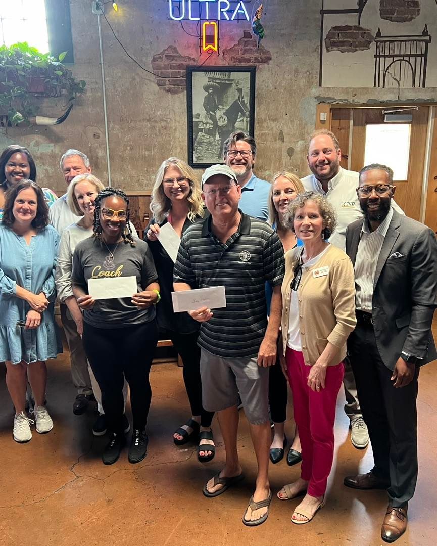 Group of people indoors, holding papers. 