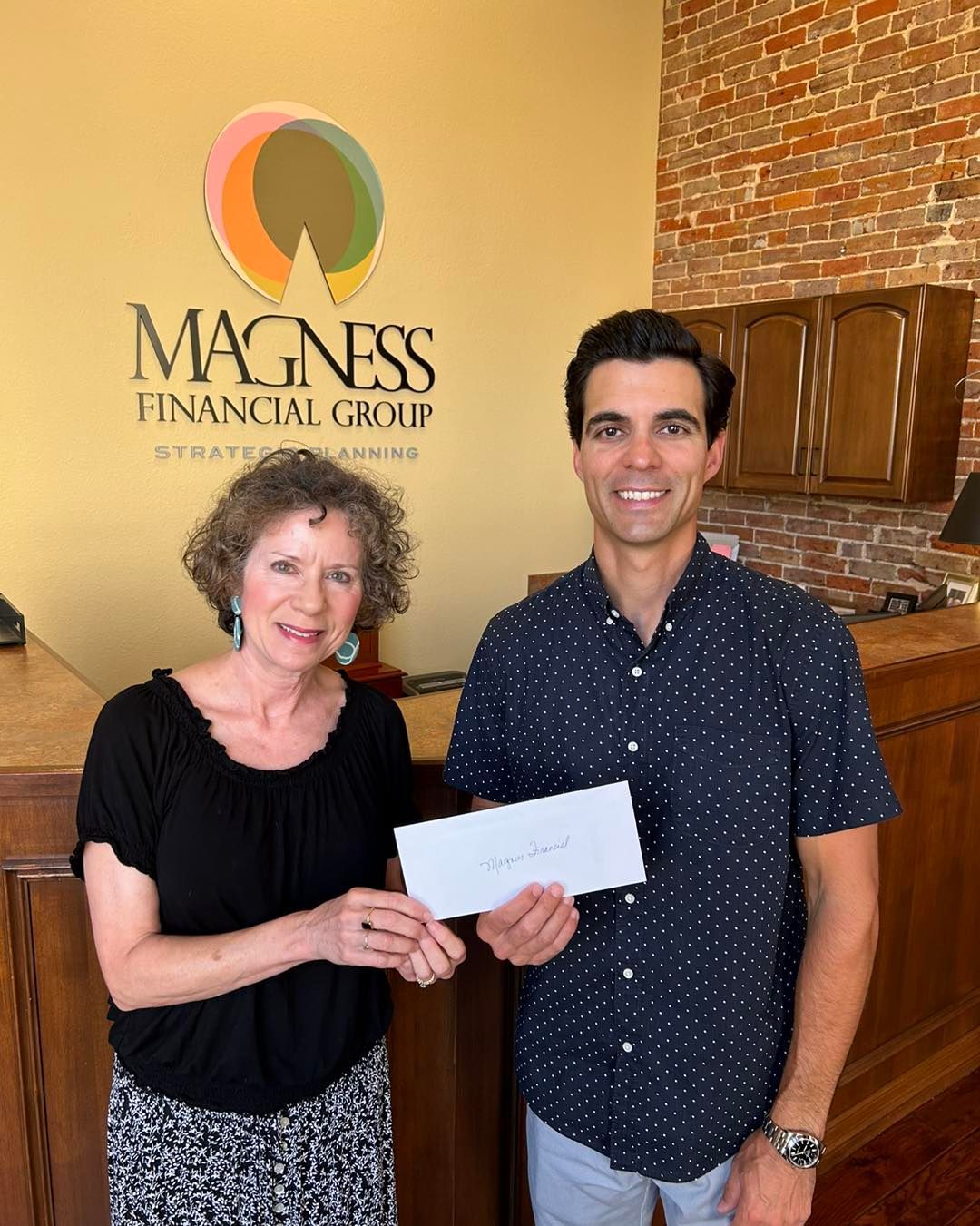 Woman and man holding envelope in front of 