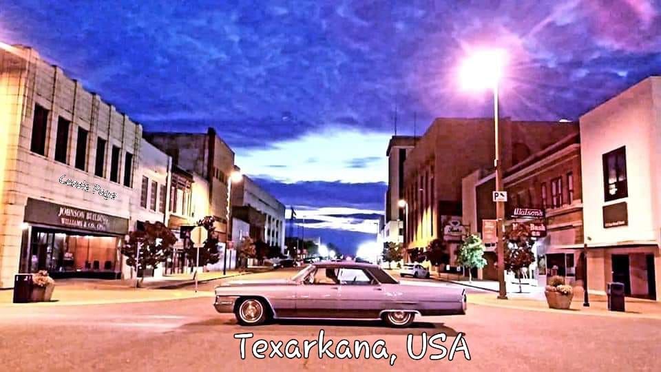 Classic light purple car on a street in downtown Texarkana, USA, at dusk, under a cloudy sky.